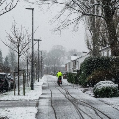 fietser die door de sneeuw rijdt met een fluohesje