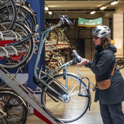 Vrouw die fiets stalt in een dubbeldek fietsenstalling