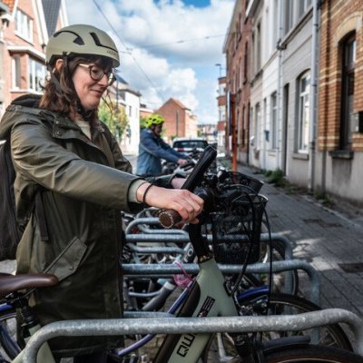 Vrouw die fiets uit fietsenrek haalt
