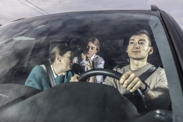 chauffeur en twee passagiers in auto die allemaal de gordel dragen