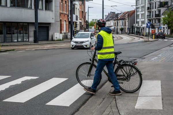 fietser met fiets aan de hand overstekend op zebrapad