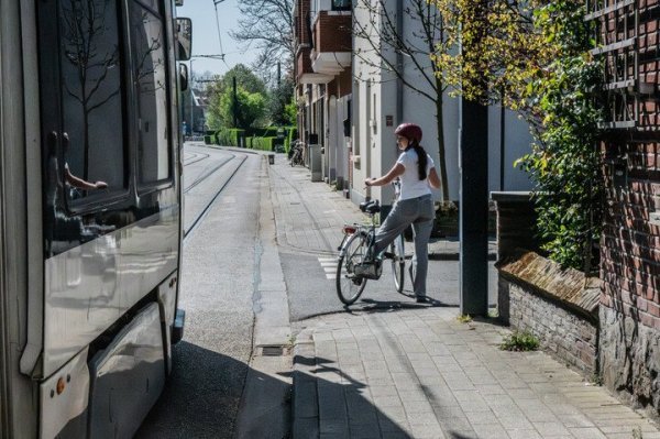 fietser wacht aan zijstraat om tram voor te laten